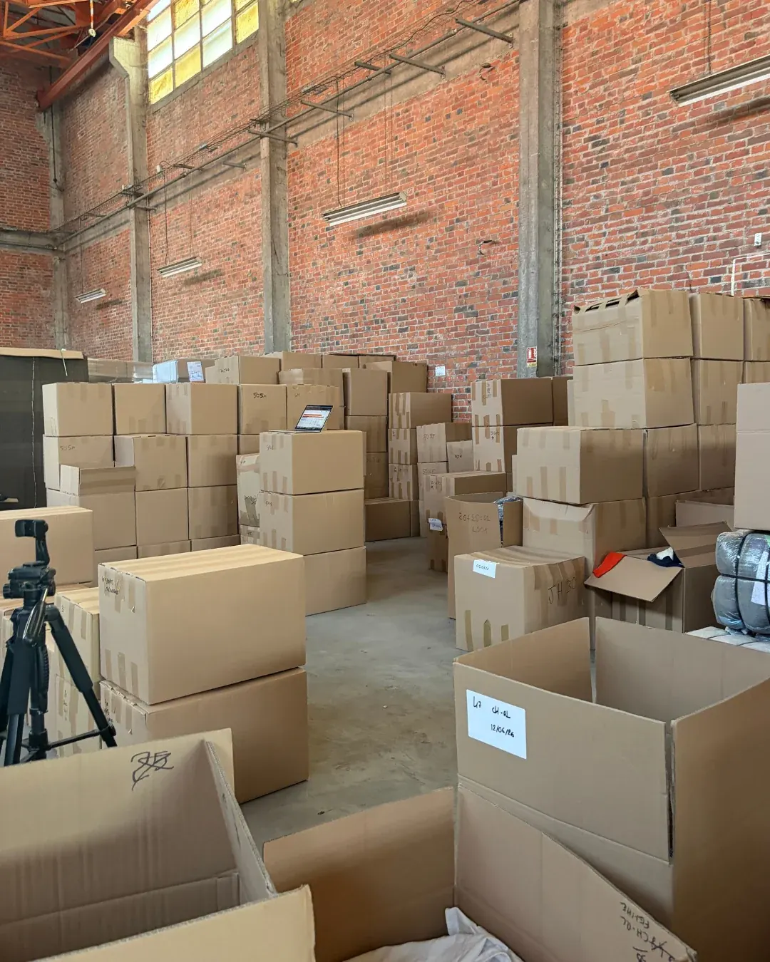Cartons de vêtements triés et étiquetés, empilés devant le mur de briques de l'entrepôt Wholesaler 2.0 à Douai